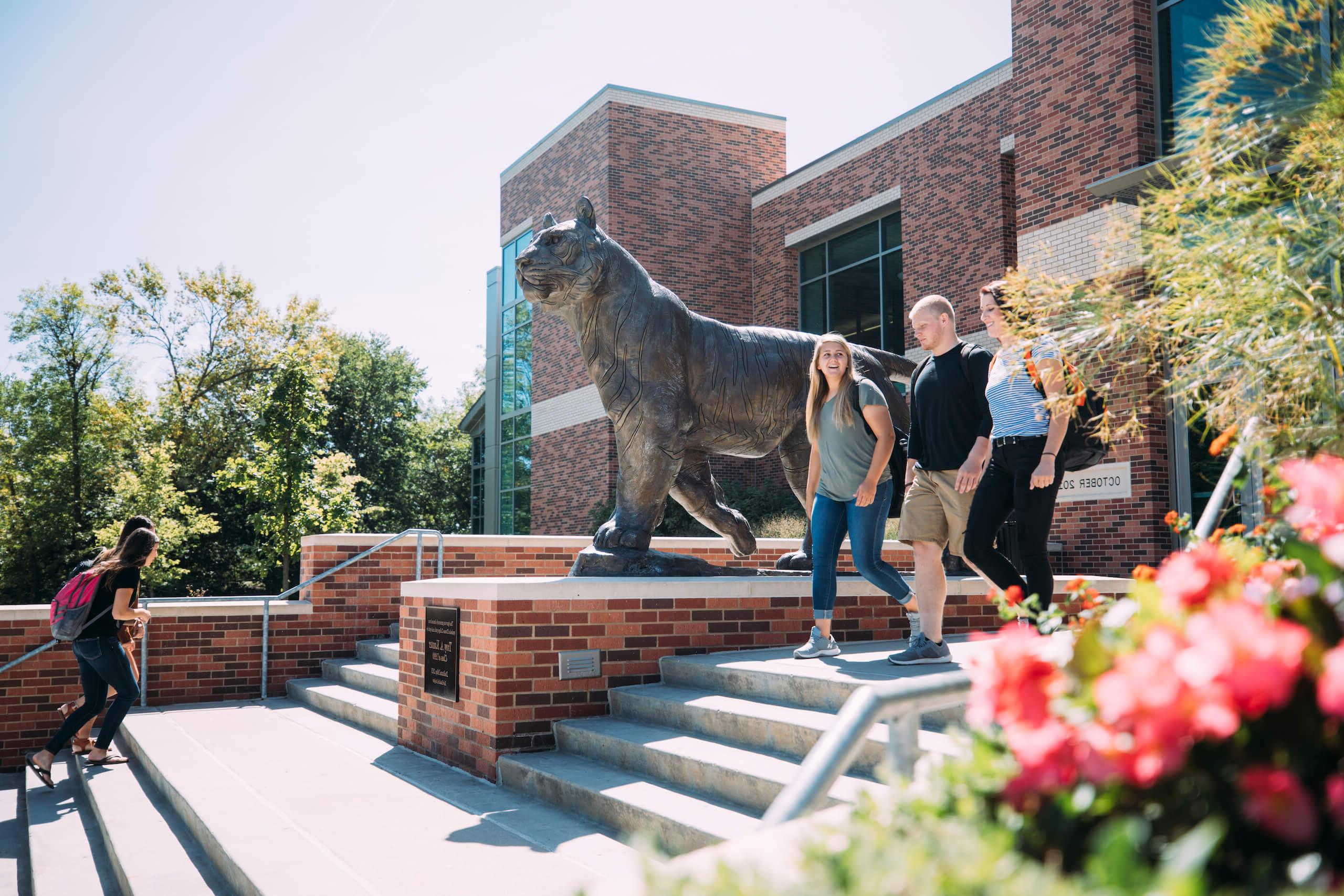 Students walking down stairs by tiger statue